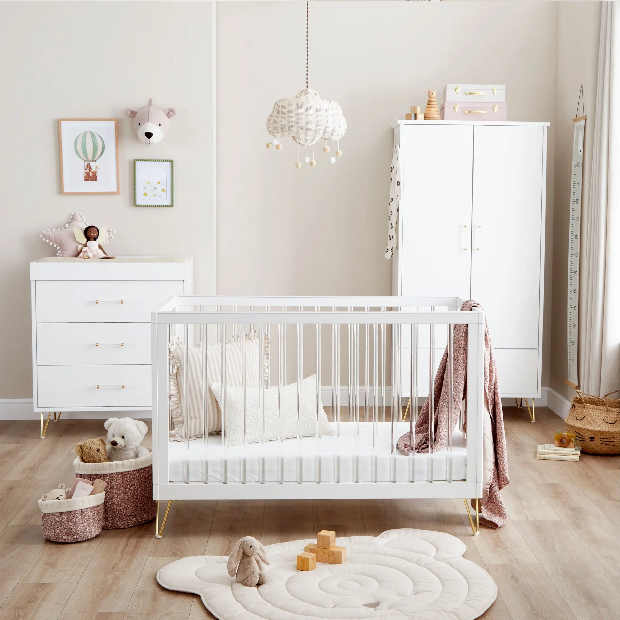 Nursery room with white crib, dresser, and toys on a wooden floor.
