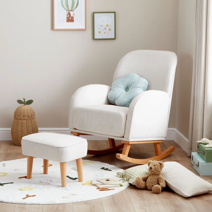  Cream rocking chair with ottoman in a child's room with toys and decor.