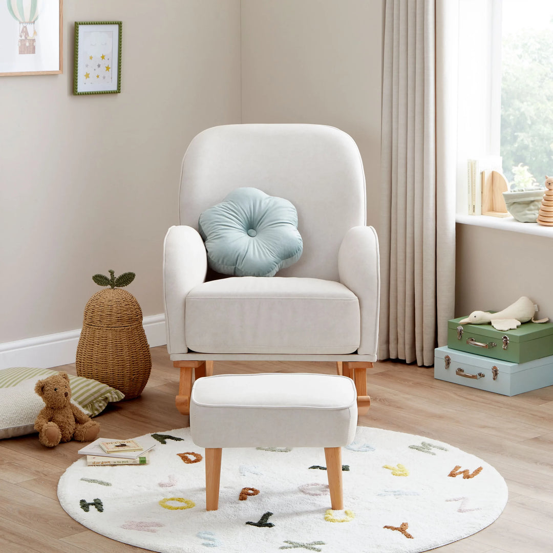 Cream armchair with a blue cushion in a child's room with toys and a rug.