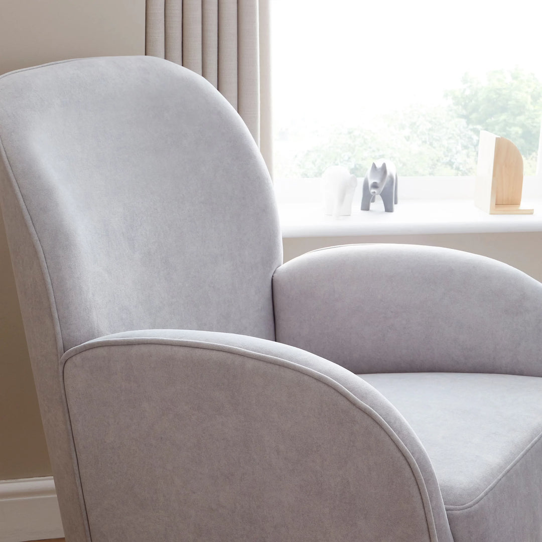 Grey armchair in a room with a window and decorative items.