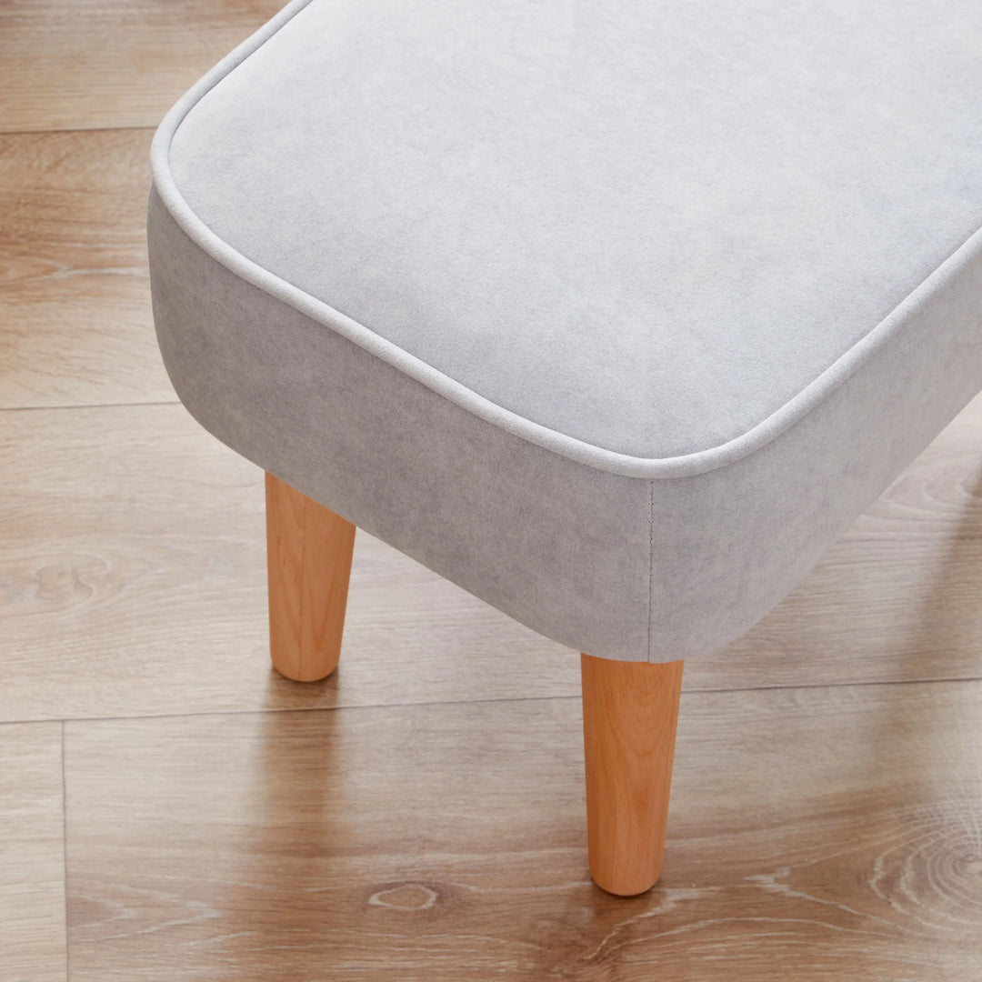Grey cushioned stool with wooden legs on a wooden floor