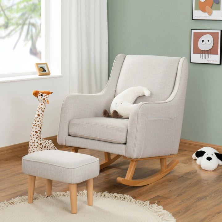 Grey rocking chair with ottoman and plush toys in a room with green walls and a window.