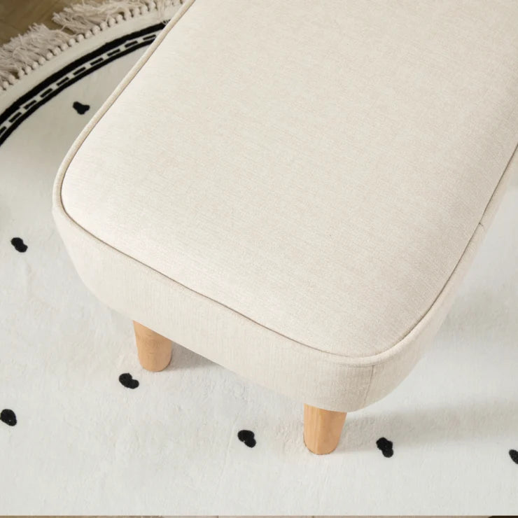 Beige stool with wooden legs on a white floor with black heart patterns