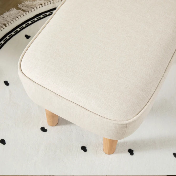 Beige stool with wooden legs on a white floor with black heart patterns