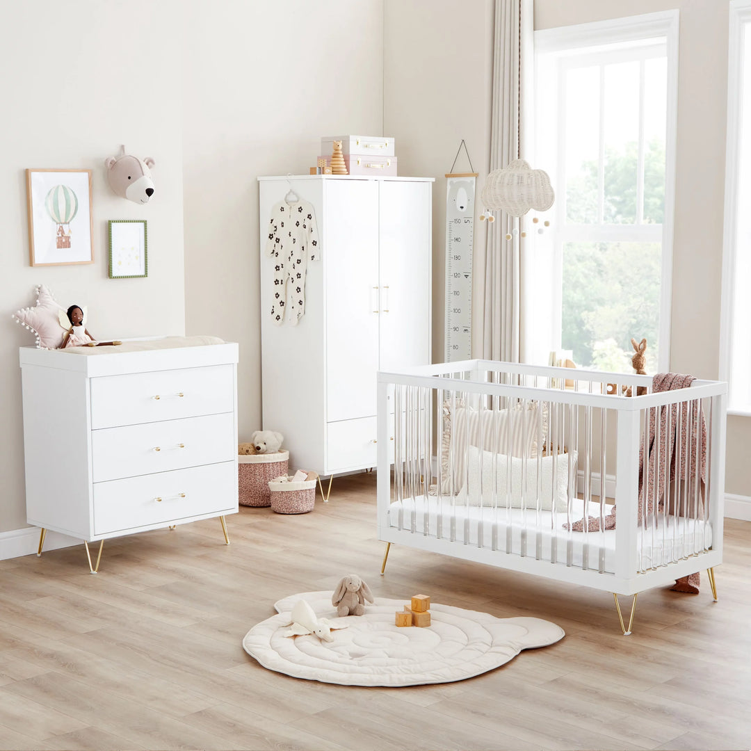 Nursery room with white crib, dresser, and wardrobe.