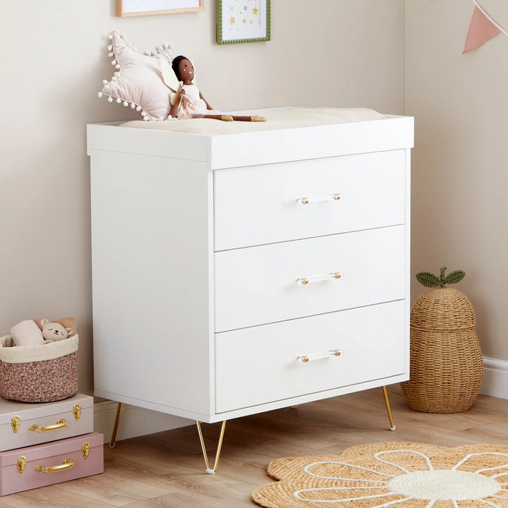 White dresser with gold handles in a child's room with toys and decor.