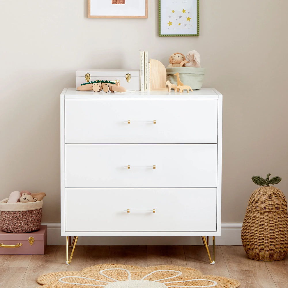 White dresser with gold legs in a nursery setting