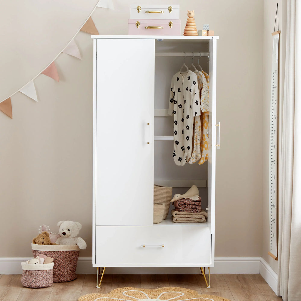 White wardrobe with gold legs in a room with toys and decor