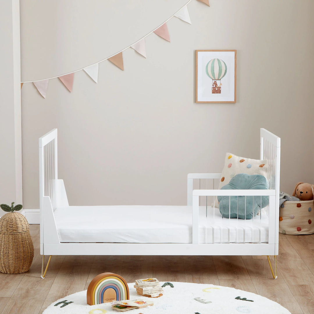 White crib in a child's room with toys and decor