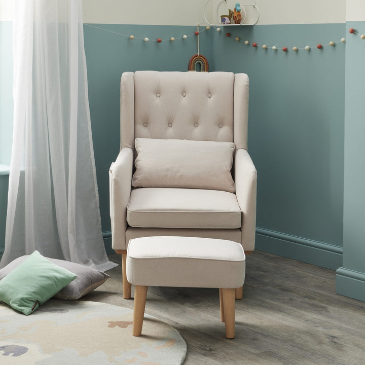 Beige armchair with ottoman in a room with teal walls and decorative elements.