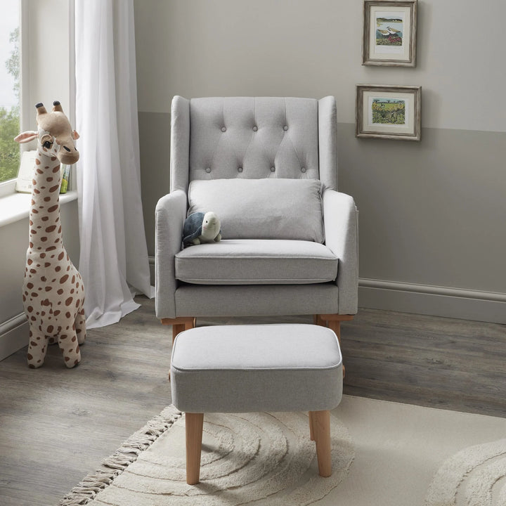 Grey upholstered rocking chair with ottoman in a nursery setting