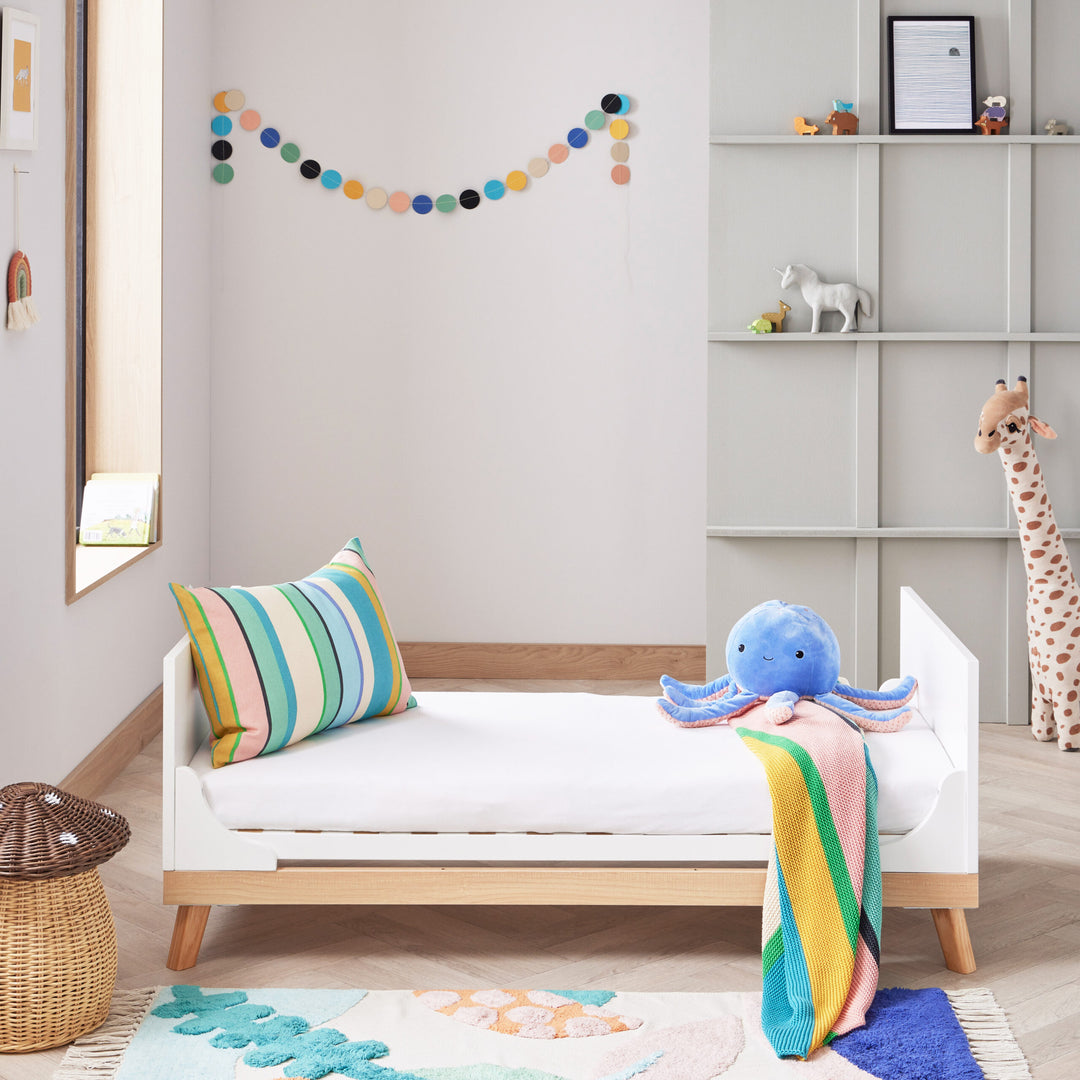 Children's room with a toddler bed, colourful pillow, and plush octopus toy.