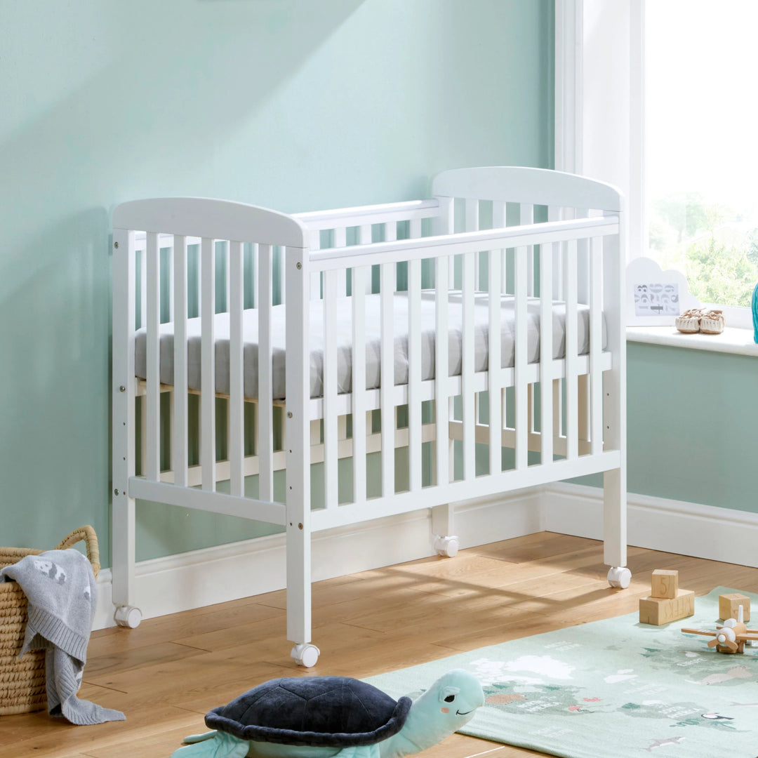 White crib in a room with light blue walls and wooden floor.