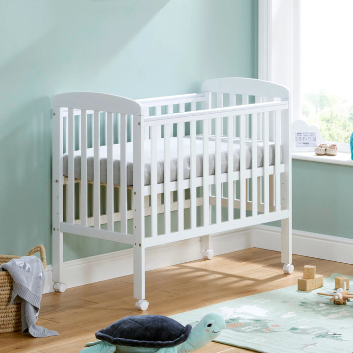 White crib in a room with light blue walls and wooden floor.