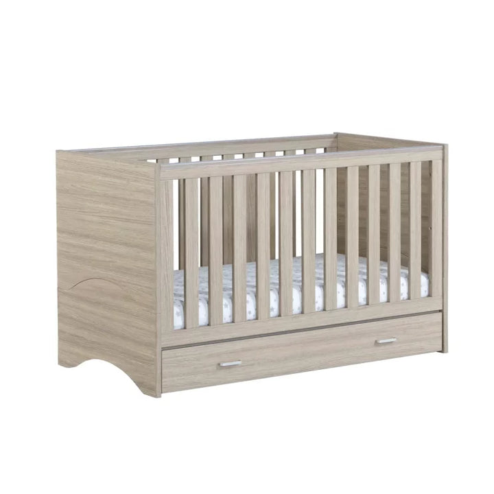 babymore Veni Cot Bed in Oak with drawer on a white background