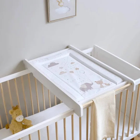 Nursery with a white changing table attached to a crib, featuring cartoon designs.
