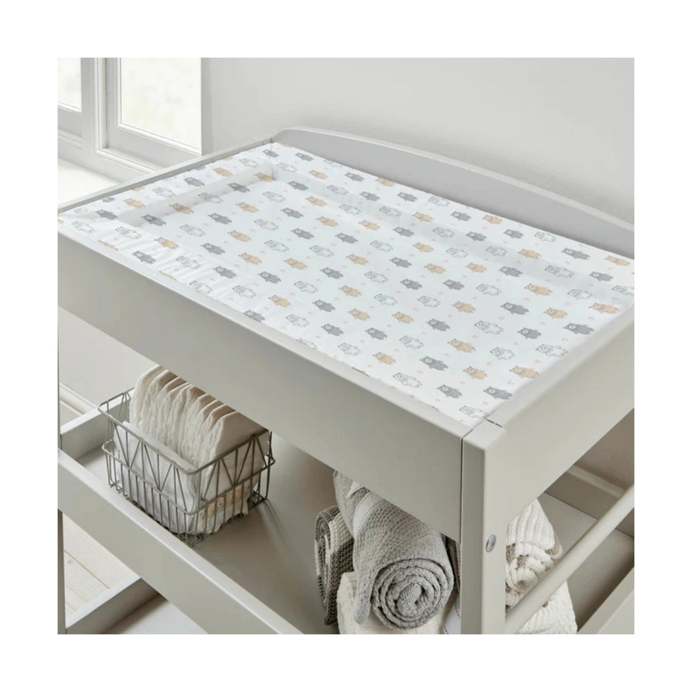 Nursery changing table with a patterned cover and folded towels underneath.