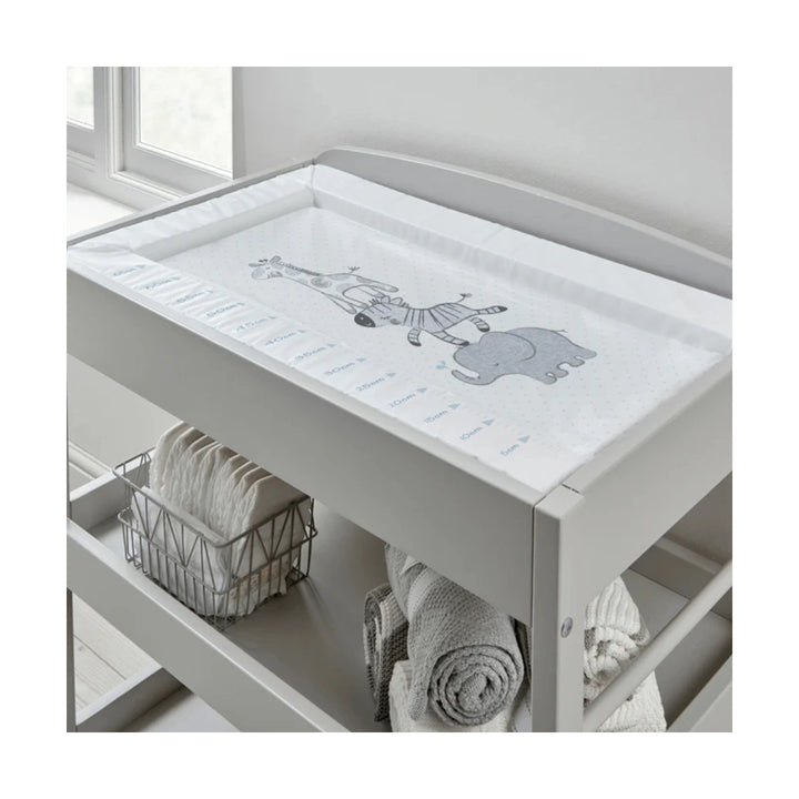 Grey changing table with a white cover featuring cartoon characters, placed against a light grey wall.