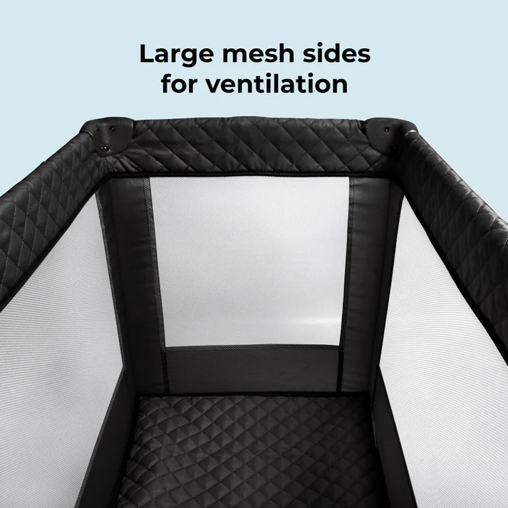 My Babiie Black Quilted Travel Cot  with large mesh sides for ventilation on a light blue background