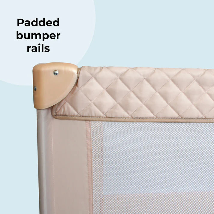 My Babiie Travel Cot in Blush Quilted padded bumper rail on a light blue background with text 'Padded bumper rails'.