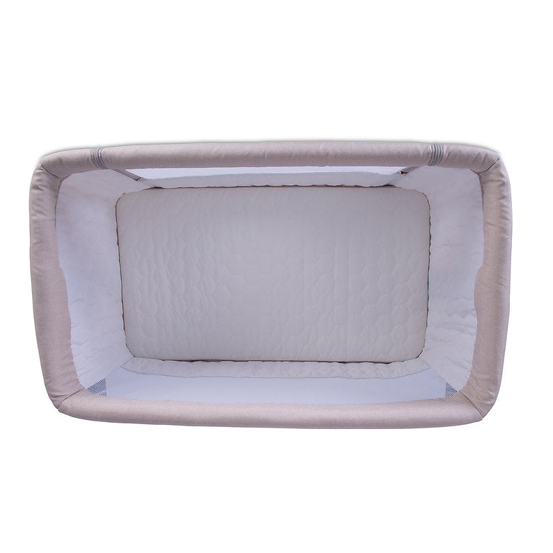 Red Kite Rockabye Bedside Crib with beige and white bedding on a white background