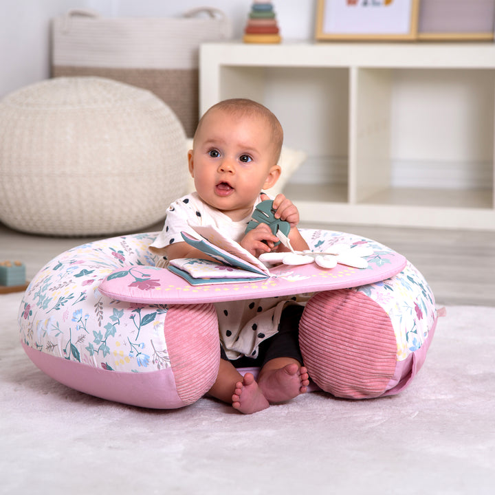 Baby sitting in Red Kite Sit Me Up Rose & Ivy with a pink base in a room setting.