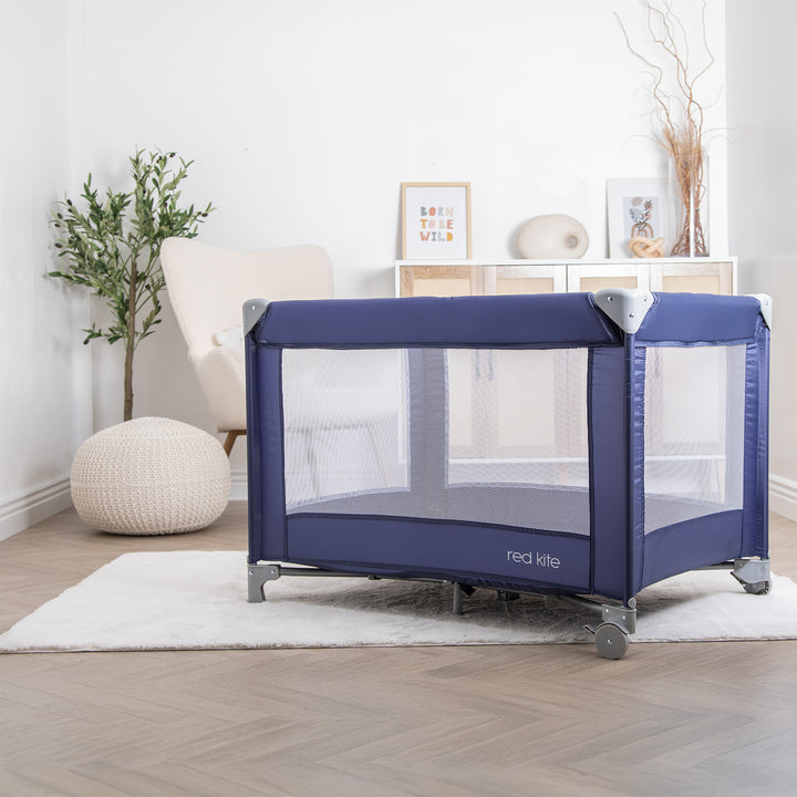 Red Kite Sleeptight Travel Cot in Blueberry with mesh side in a room setting