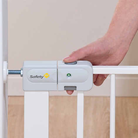 Hand operating a white baby gate with a visible Safety 1st logo.
