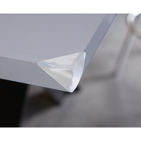 Triangle-shaped clear plastic corner protector on a gray surface